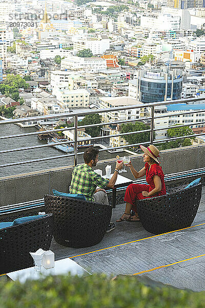 Man and woman in love toasting with cocktails on a rooftop bar