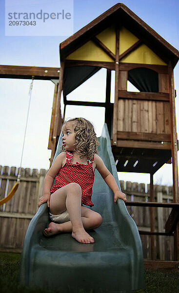 Profile toddler with blond curls on playground slide