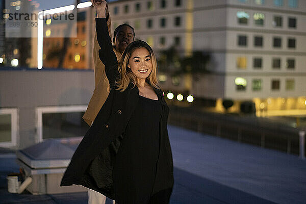 Multi racial couple dancing on an urban downtown roof-top at nig