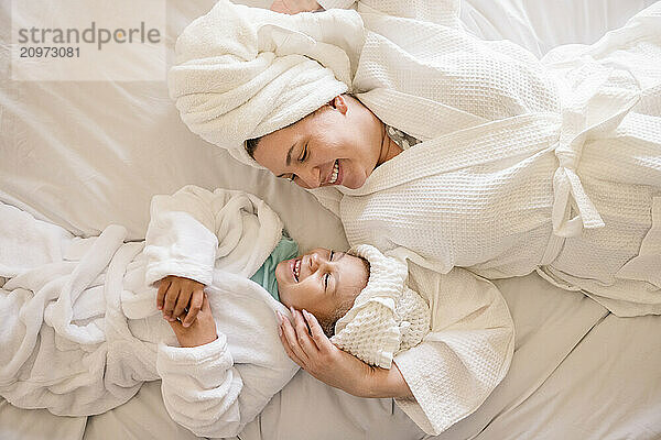 Mother and daughter laughing with each other laying on their backs