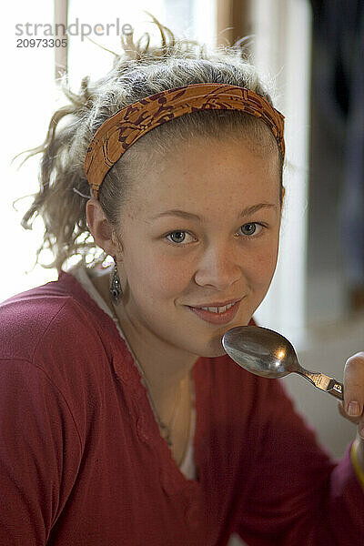 Teenage girl holding a spoon and smiling  Maine  USA.