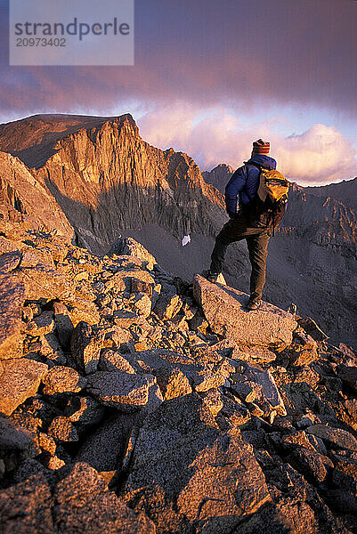 Man hiking at dawn over talus on Split Mountain in the John Muir Wilderness  CA  USA.