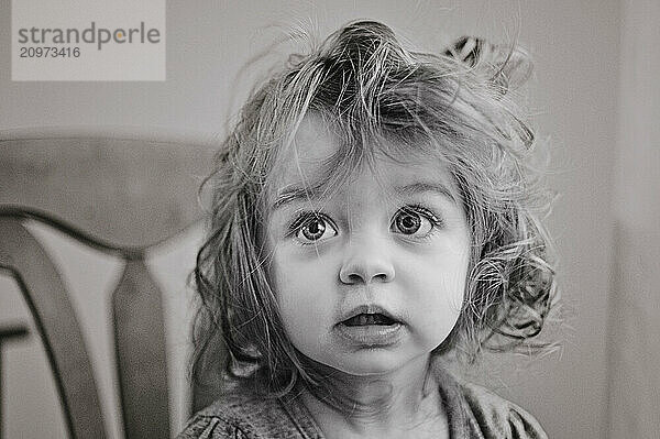 Portrait of beautiful toddler with messy hair and wide eyes