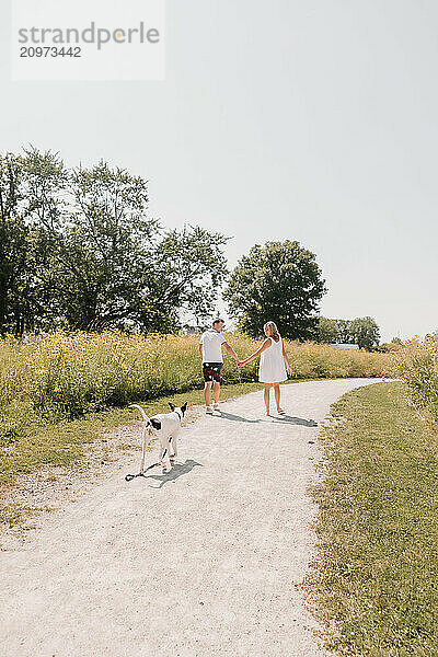 Young Couple walking with dog on path lined with wildflowers