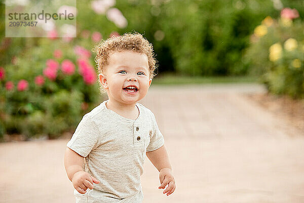 Baby boy laughing in a garden of roses