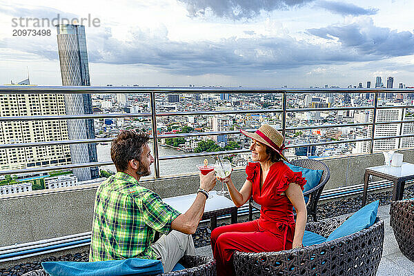 Happy couple enjoying a cocktail on a rooftop bar  Bangkok