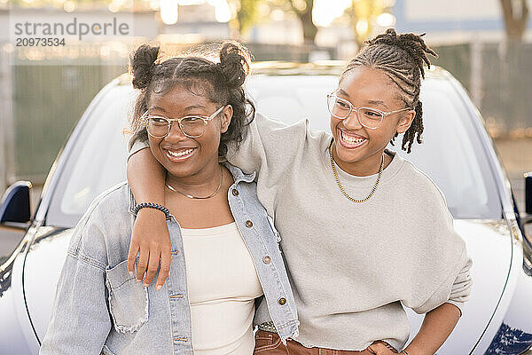 Young african american women laughing together in front of car