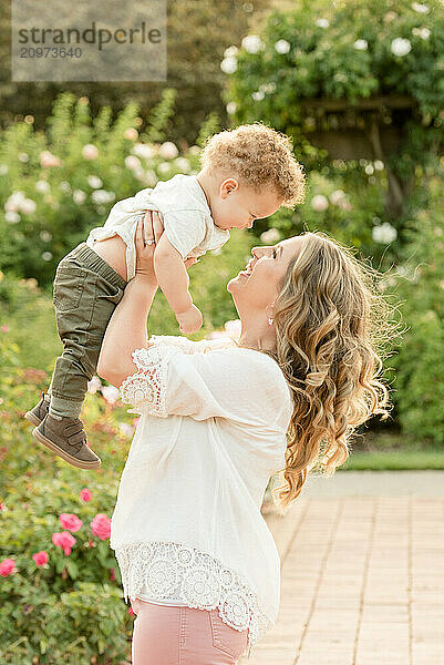 Mother lifting son in the air in garden