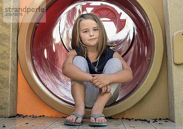 Pretty young girl resting on playground equipment summer