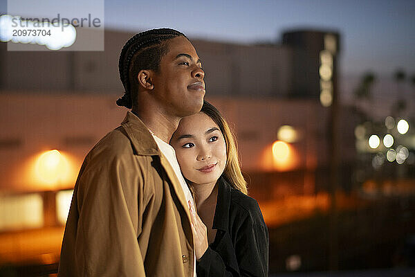 Asian female and african american black male embrace on a roof-t