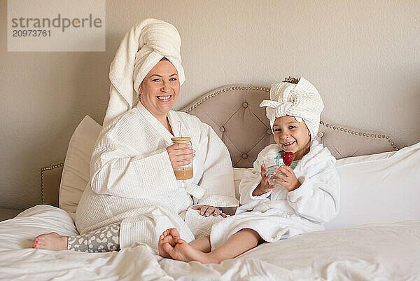 Mother and daughter wearing robes and towels in their hair