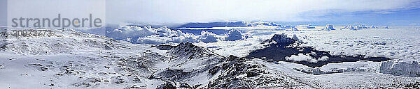 Climbers ascending the crater rim of Mt. Kilimanjaro  up from Stella Point  with Mawenzie Peak  and Rebmann Glacier seen.