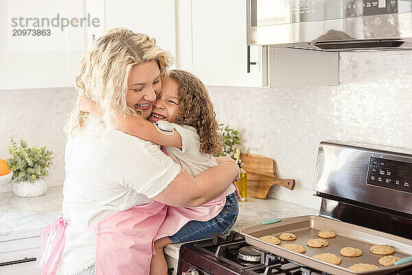 Mother and daughter hugging each other and laughing in the kitchen