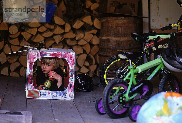 A child plays inside a cardboard television on a porch in Maine.