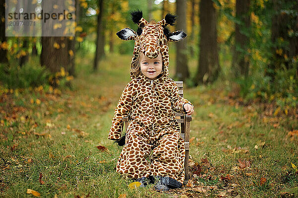 Happy little girl wearing Giraffe costume in colorful woods