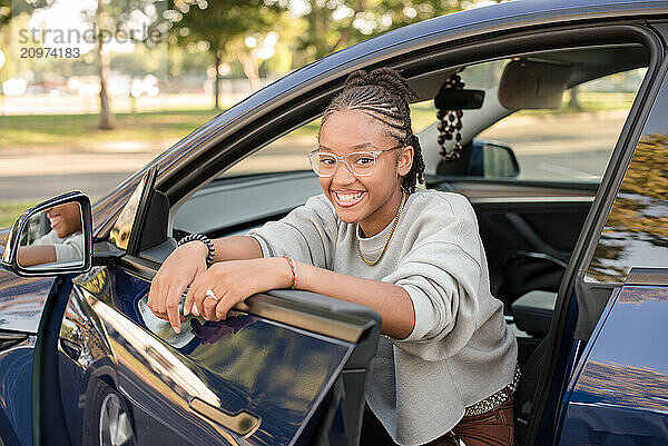 Adult driver leaning on car door smiling