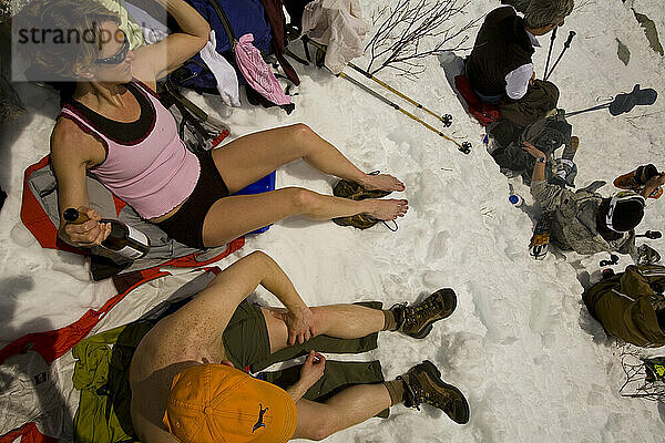 Friends lounge in the snow on a sunny day at Tuckerman Ravine in Mount Washington in the White Mountains of New Hampshire.