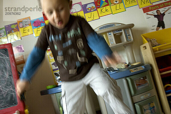 A boy jumps up and down in his play room