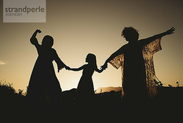 Silhouette three women twirling dancing beach sunset Spain