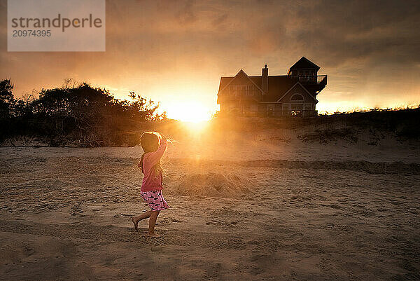 Young girl walking on sandy beach in vibrant sunset