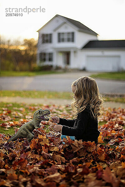 Profile toddler with blonde curls playing in colorful fall leaves