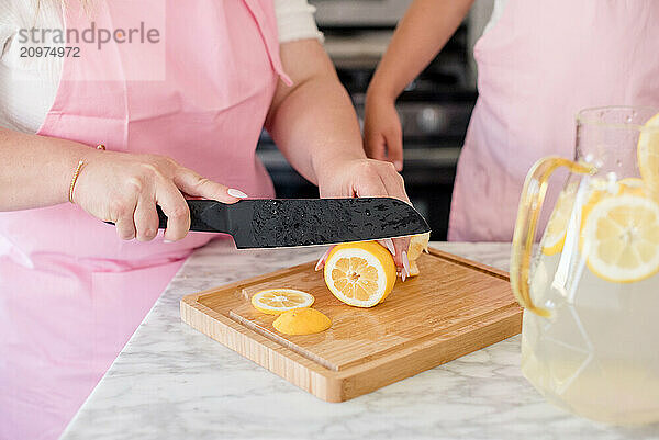 Mother slicing lemons on a cutting board in the kitchen for lemonade