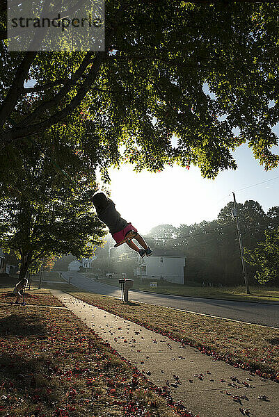 Young girl in tree swing sunny fall day