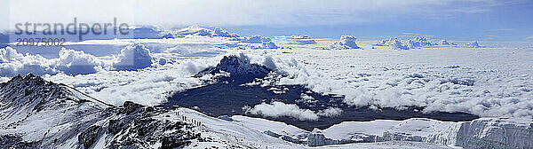 Climbers ascending the crater rim of Mt. Kilimanjaro  up from Stella Point  with Mawenzie Peak  and Rebmann Glacier seen.