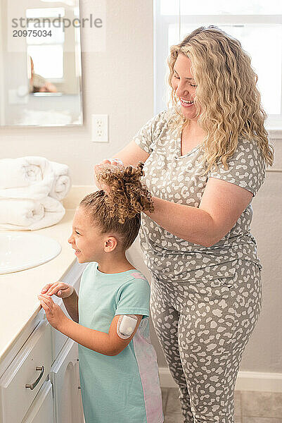 Mother putting daughters hair up in their pajamas