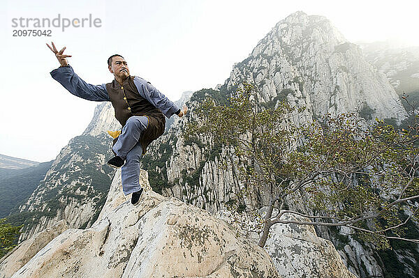 Shaolin Monk Shi De Jian of the San Huang Zhai Monastery demonstrates traditional martial arts on the mountainside of Song Mountain.