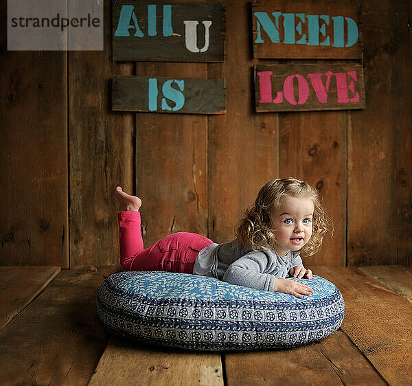 Beautiful toddler relaxing on floor pillow indoors