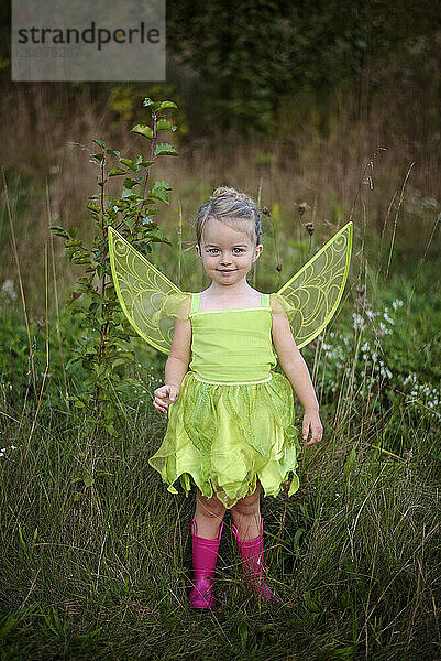 Beautiful toddler in green fairy costume and pink boots