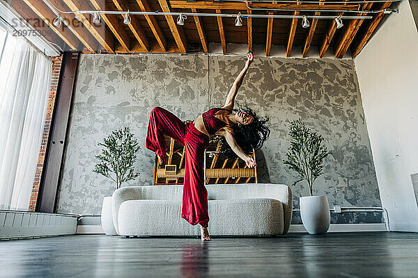 Woman dancing energetically in a loft with red outfit