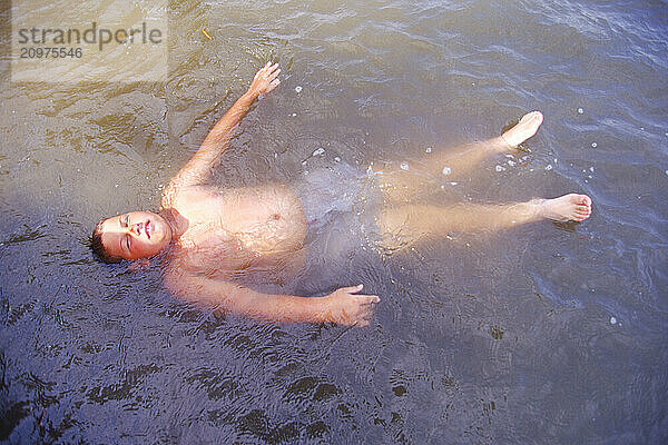 Boy floating in a river.