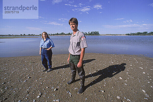 Two people on a riverside.