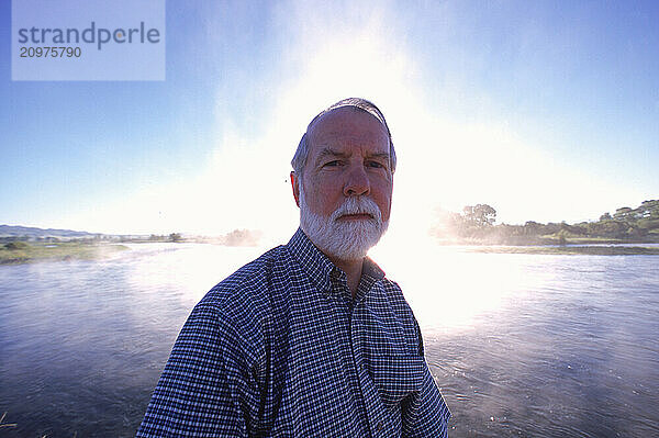 Man standing next to a steaming pool.