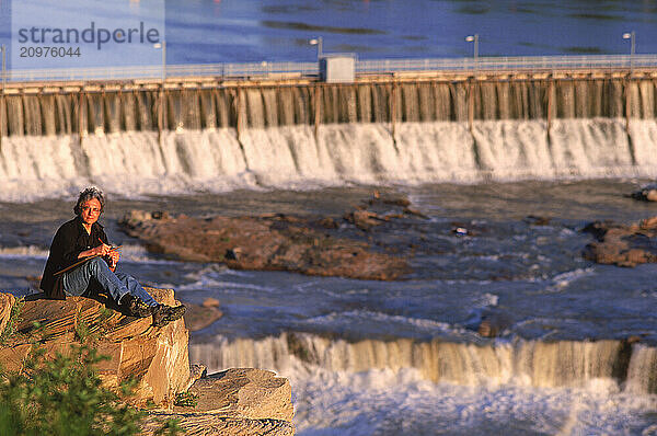 Man sitting by a dam.