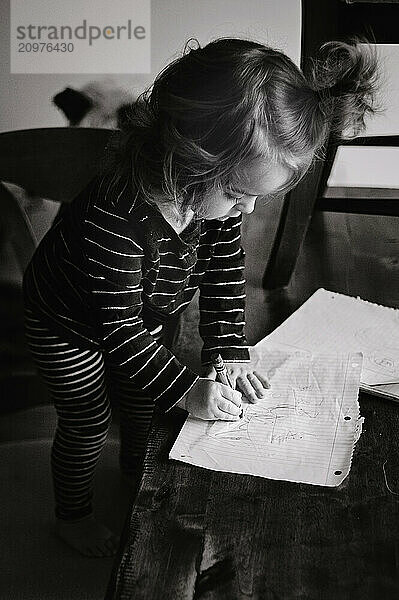 Female toddler with pigtail writing on notebook paper