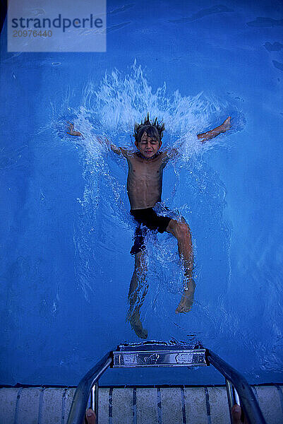 A young boy splashes into a swimming pool in Florida.