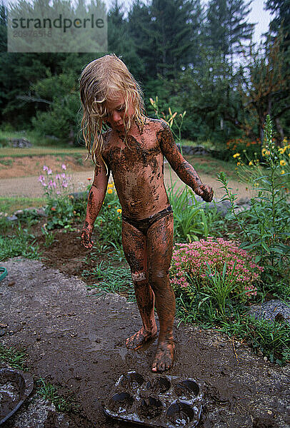 A young girl plays in the mud  Lovell  Maine  USA.