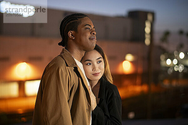 Asian female resting her head on an african american's shoulder