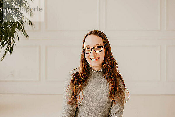 Smiling young Hispanic woman in gray sweater  clean indoor setting