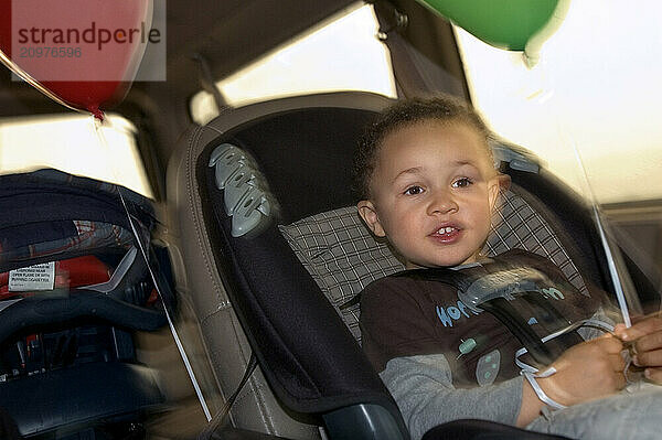 A boy rides in his car safety seat