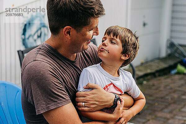 Father holding son with chocolate on face  both smiling