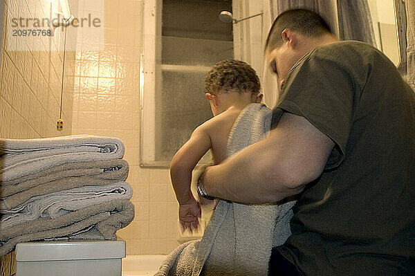 A father towels off his son after the evening bath.