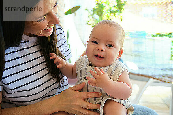 Mother holding and looking at her baby boy smiling