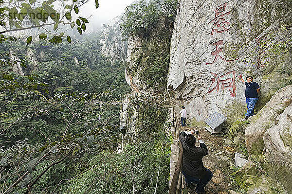 Tourists pose for pictures on the trail to the San Huang Zhai Monastery on Song Mountain.