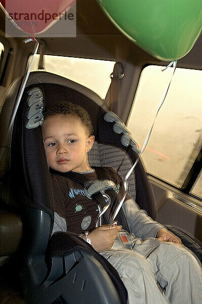 A boy rides in his car safety seat