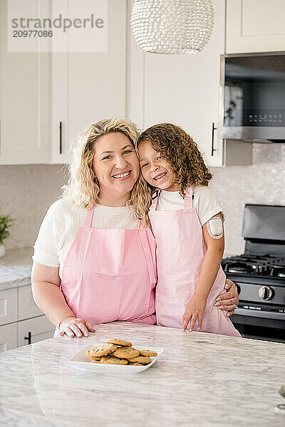 Mother and daughter smiling at camera in the kitchen