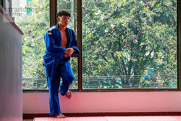 Judo fighter portrait next to window with some trees at background